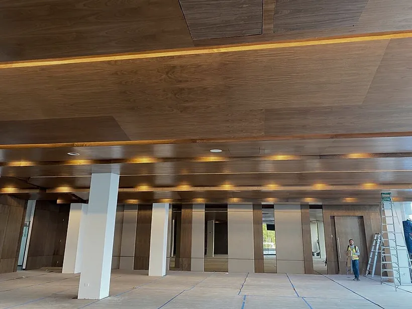 Salón del Club Alpino Chipinque en obra: plafón de madera con iluminación indirecta, columnas blancas y el piso protegido