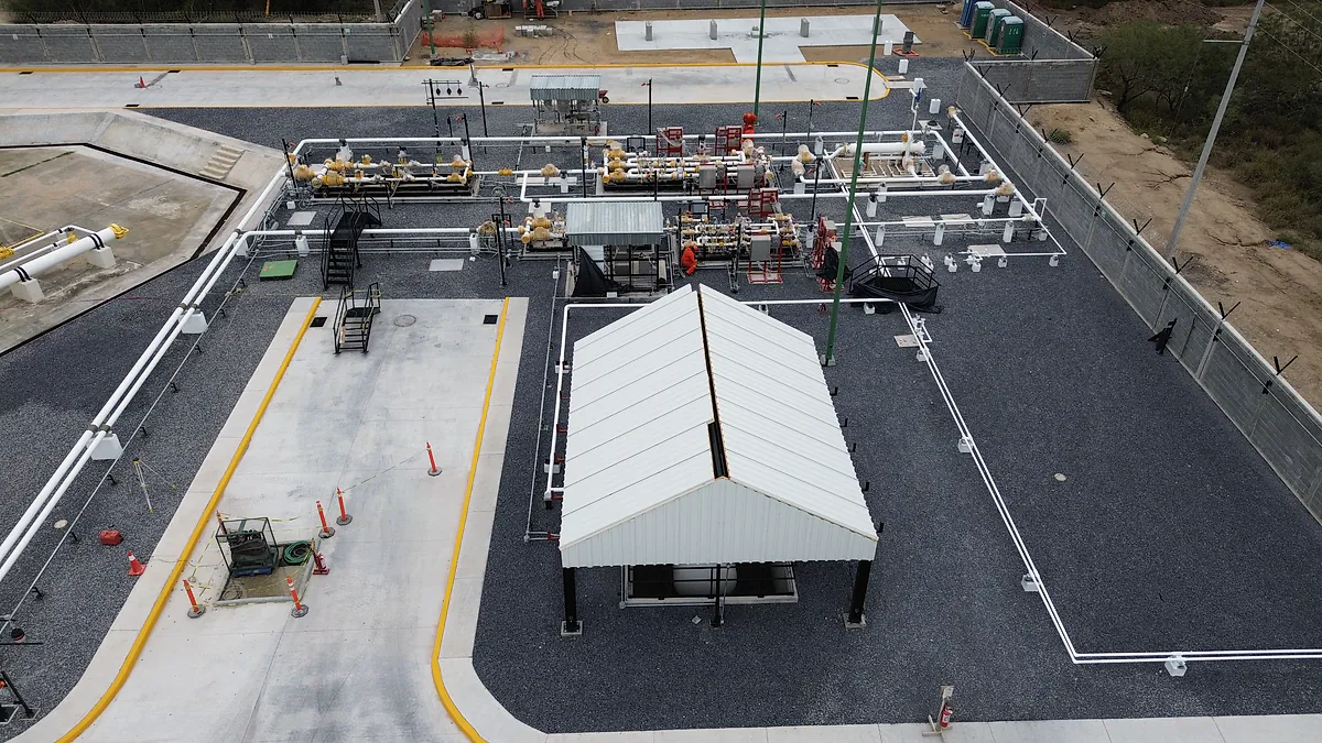Vista aérea de la Estación Anzalduas del gasoducto Libramiento Reynosa: vialidad de concreto con guarniciones amarillas, cobertizo y tuberías sobre grava
