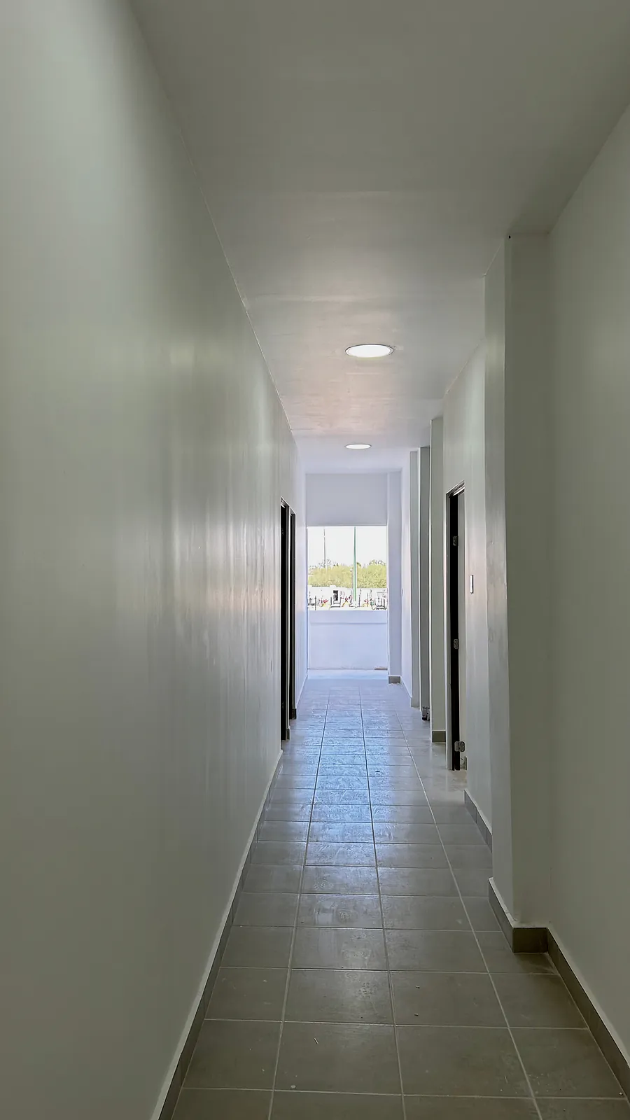 Pasillo interior terminado, con muros blancos, luminarias empotradas en el plafón y piso cerámico, en el gasoducto Libramiento Reynosa