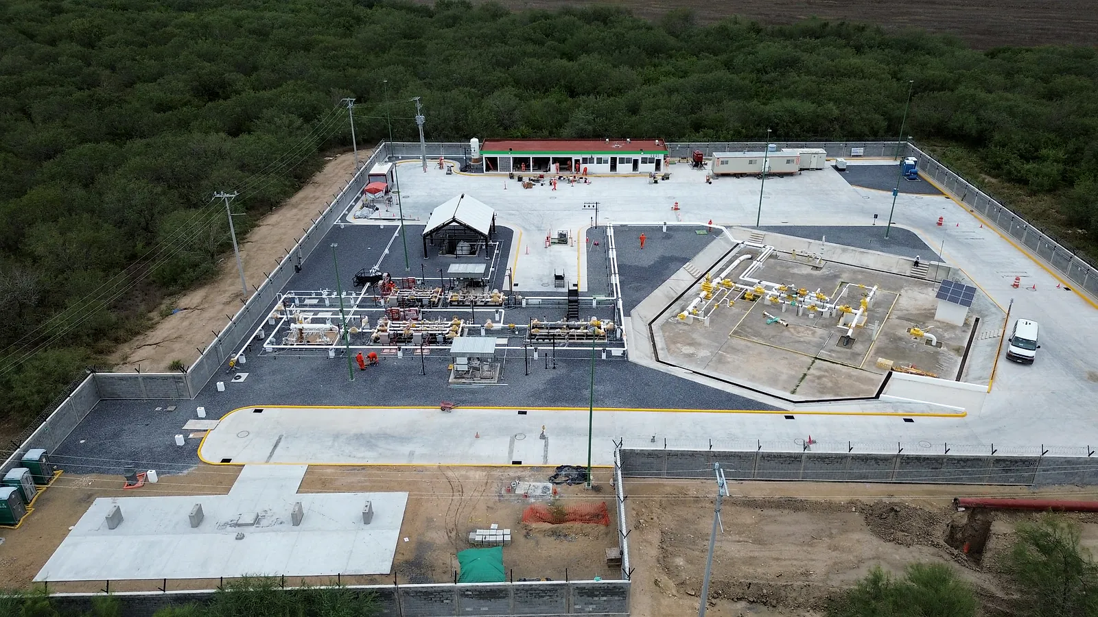 Vista aérea de la Estación Anzalduas rodeada de monte, con las vialidades de concreto, el patio de grava de las tuberías y la barda perimetral