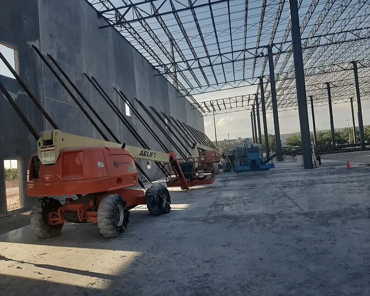 Interior de una nave del Parque Colonial REI XB Logistics: muros de concreto apuntalados, estructura metálica de cubierta y plataformas elevadoras